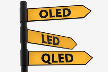 Vägvisare med gula pilar med text för OLED, QLED och LED som pekar åt olika håll. 