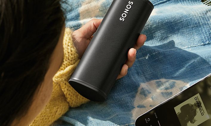 Kvinna som håller i Sonos Roam och telefon