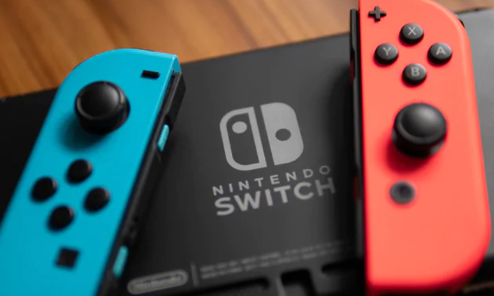 Nintendo Switch konsoler, en turkos och en korallfärgad med nintendo loggan på svart bakgrund i mitten.