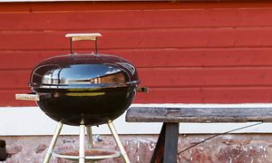 Grill framför ett rött hus