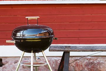Grill framför ett rött hus
