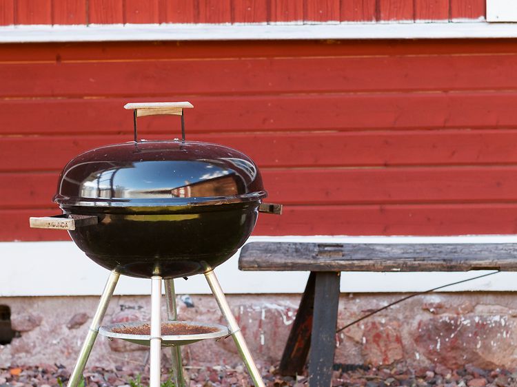 Grill framför ett rött hus