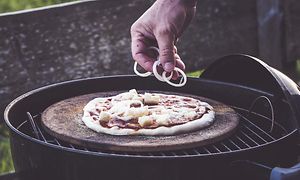 En hand som lägger topping på en pizza