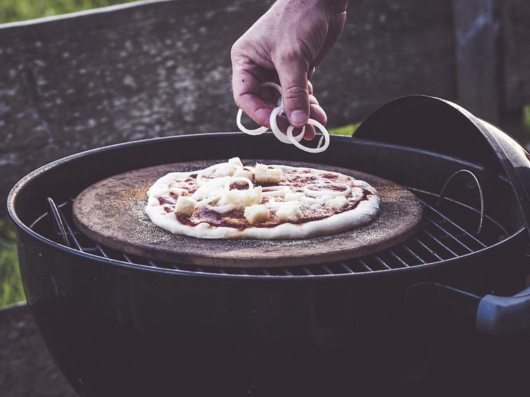 En hand som lägger topping på en pizza