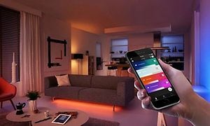Smart hem: En hand med smart telefon som fjärrstyr belysning.