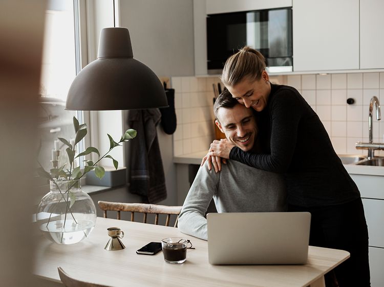 Couple in a kitchen in front of a laptop