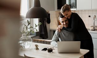 Par i ett kök framför en bärbar dator.
