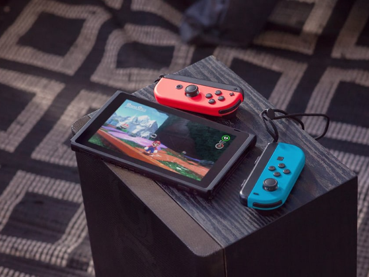 Nintendo Switch - med två joycons på ett litet bord, en rutig matta syns i bakgrunden.