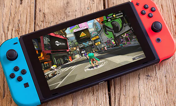 Nintendo Switch enhet, som är blå på ena sidan och röd på andra, placerad på ett träbord.