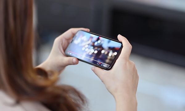 Närbild av en kvinna som ser på video i sin mobiltelefon.