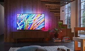 En stor TV med starka färger och starkt ljus lyser upp ett helt vardagsrum.  