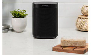 Sonos smarta svarta högtalare placerad på en vit byrå