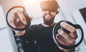 En man gamear med VR-glasögon och en kontroll i varje hand