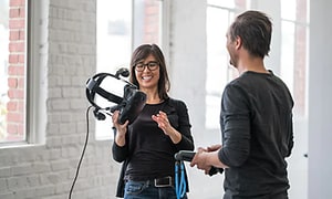 En kvinna visar och demonstrerar VR-glasögon för en man.