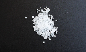 En hög med vanligt vitt flingsalt på en svart bänk.