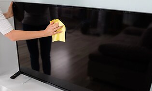 En person rengör en TV-skärm med en mikrofiberduk.
