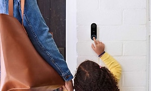 En liten flicka / ett barn ringer på en smart dörrklocka 
