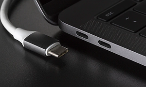 Närbild på vit USB-C sladd som ligger vid sidan av ingången på datorn.