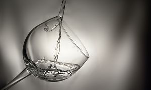 Vatten hälls ned i ett vinglas. 