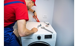 En anställd installerar en tvättmaskin vid leverans