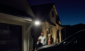 Familj som står under Floodlight camera framför ett hus