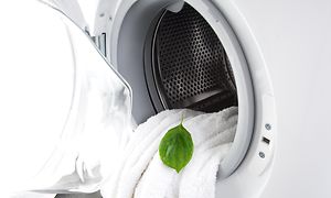 Vit handduk i en tvättmaskin med ett grönt löv