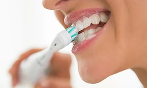 Närbild på munnen på en person som borstar tänderna med en eltandborste.