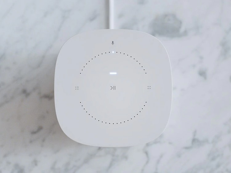 Vit Sonos One-högtalare med touch-knappar placerat på ett marmorbord. 