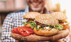 En man som håller i en tallrik med hamburgare