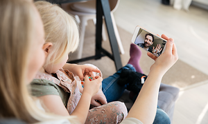 En mamma och hennes dotter pratar med pappan i ett videosamtal