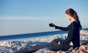 En kvinna tittar på sin smartphone på stranden