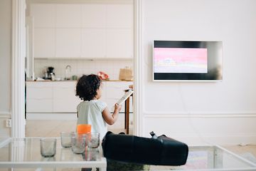 Brown goods-TV-Little girl holding remote control in front of a TV
