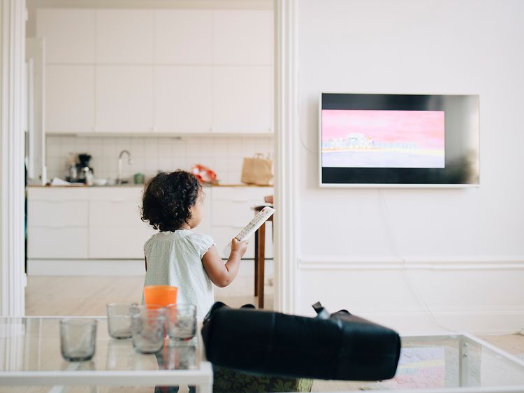 Brown goods-TV-Little girl holding remote control in front of a TV