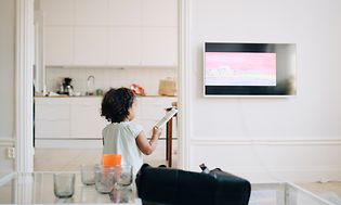 Brown goods-TV-Little girl holding remote control in front of a TV