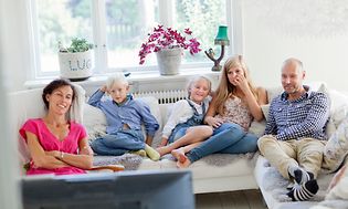 Family sitting in sofa in front of a TV