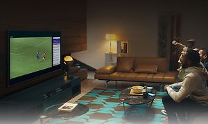 Ett gäng sitter i en soffa i ett vardagsrum och ser på fotboll på en Samsung TV.