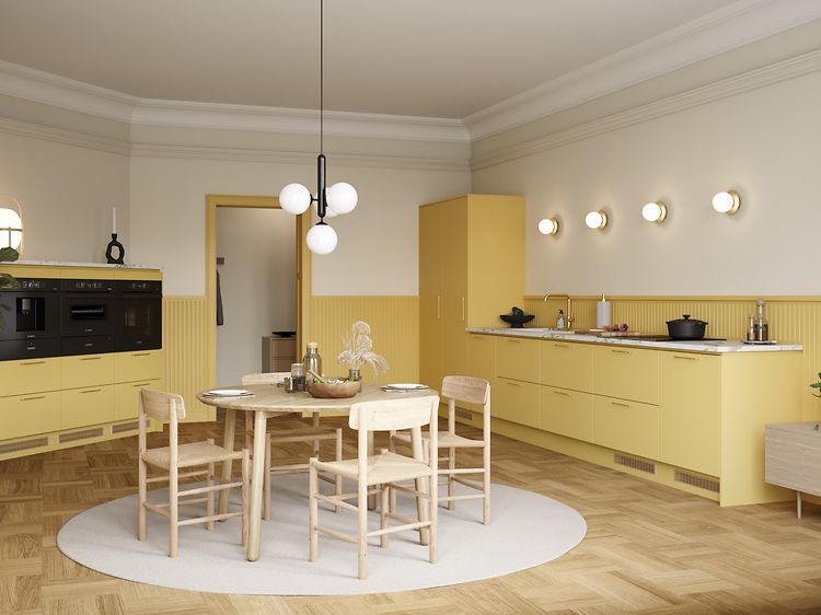 Gult Epoq Trend Mellow-kök, med bänkskiva i marmorlaminat, integrerad ugn, kaffebryggare, runt matbord och stolar.