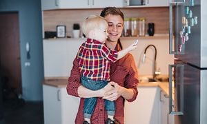 Man holding little boy in front of a stainless fridge