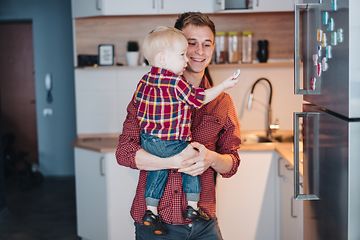 Man holding little boy in front of a stainless fridge