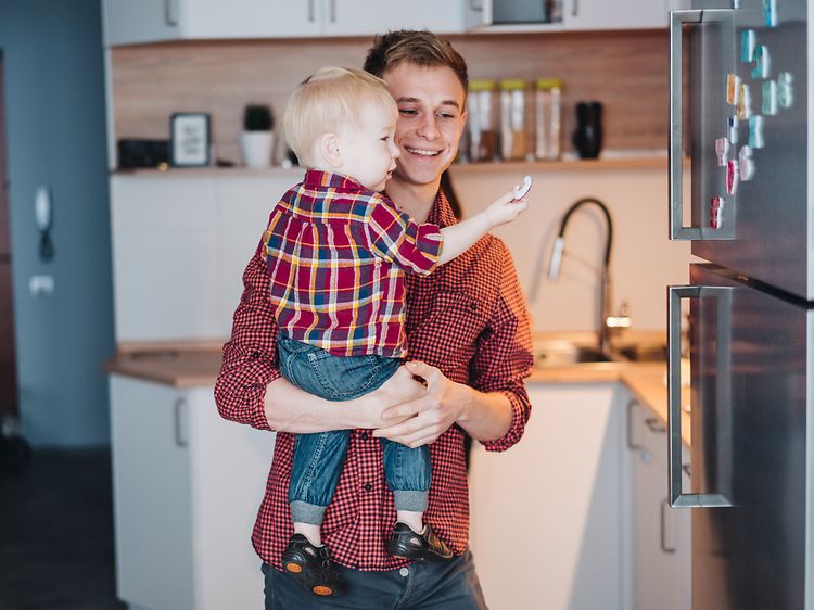 Man holding little boy in front of a stainless fridge