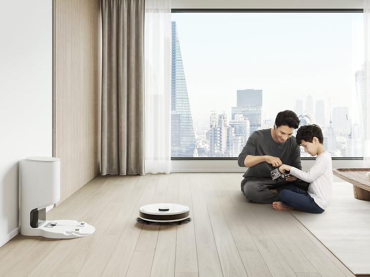 Ecovacs DEEBOT-N8 med man och pojke som sitter på ett golv framför stort fönster