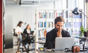 Man is smiling in front of a computer in office
