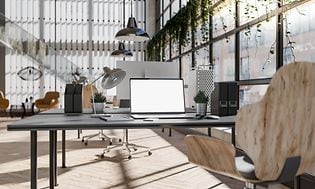 Kontorlandskap med datorer, skrivbord, stolar och stora fönster