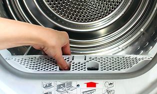 MDA-Tumble dryer-A woman holds a lint trap from a front-loading tumble dryer