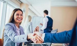 Kvinna som ler och skakar hand med en annan person