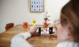 Kvinna som fotar föremål på ett bord med sin iPhone