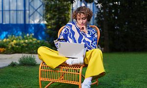Kvinna som sitter i en trädgård på en gul stol