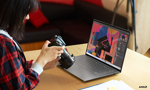 Kvinna som håller DSLR-kamera framför laptop
