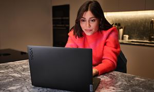 Kvinna som sitter med laptop i ett kök