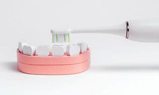Plastunderkäke med tänder som illustrerar ett barns mun tillsammans med en eltandborste